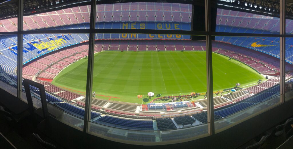 Wide view of Camp Nou stadium showcasing its vast seating and green pitch.